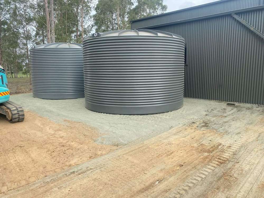 Two water tanks sitting on a level prepared sand pad